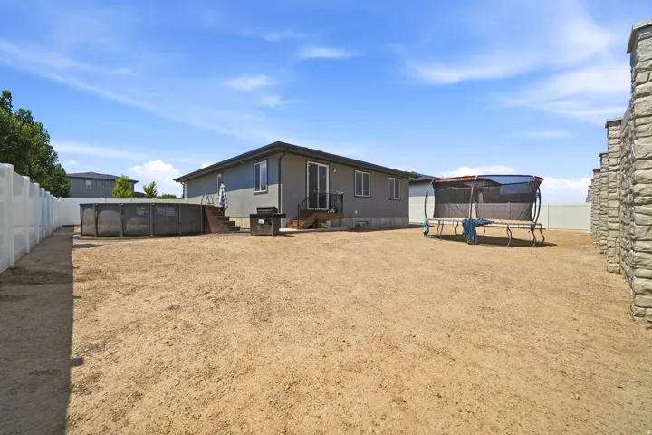 Expansive backyard featuring an above-ground pool, stucco exterior, and privacy fencing