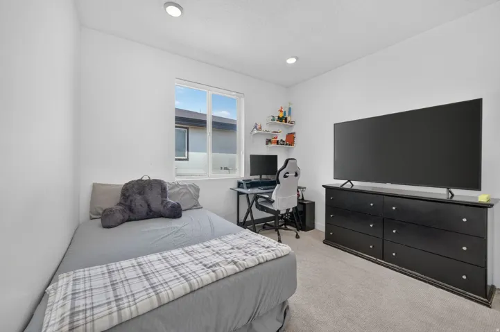 Recessed ceiling lighting, white walls, window with a white frame, light-colored carpeting, and a built-in shelving unit