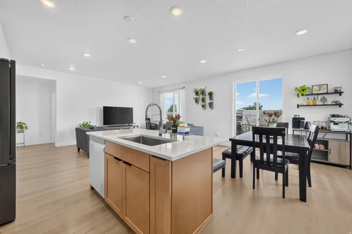 Kitchen island with integrated sink, light wood-finish flooring, recessed ceiling lighting, and sliding glass door