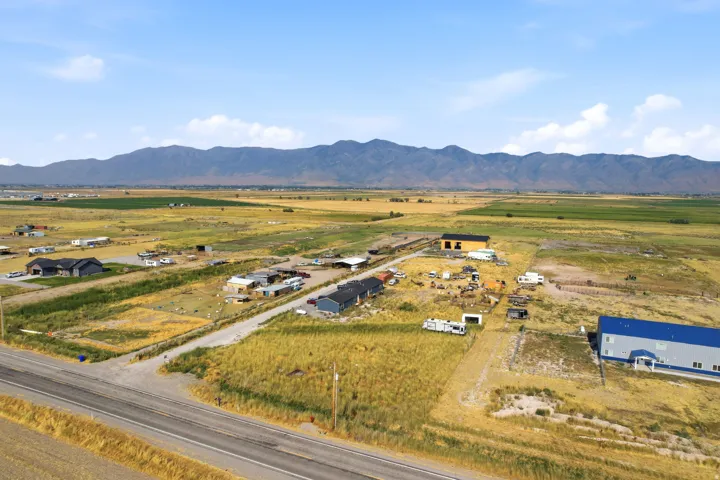 Expansive rural landscape featuring a paved road, scattered residential structures, and undeveloped land