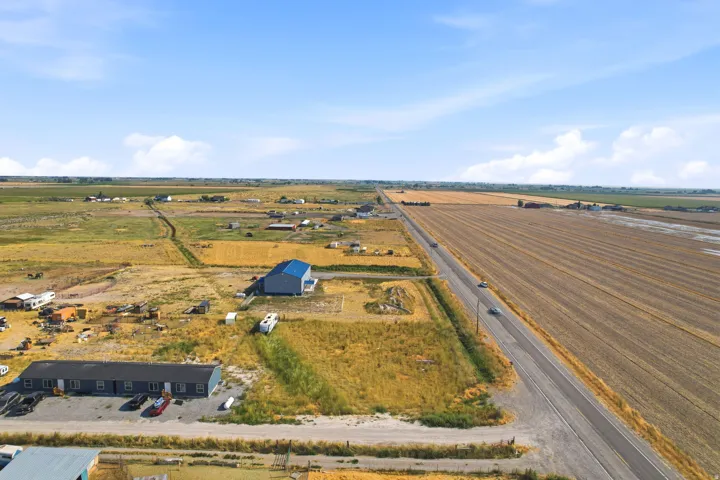 Expansive agricultural landscape featuring a paved road, cultivated fields, and multiple buildings