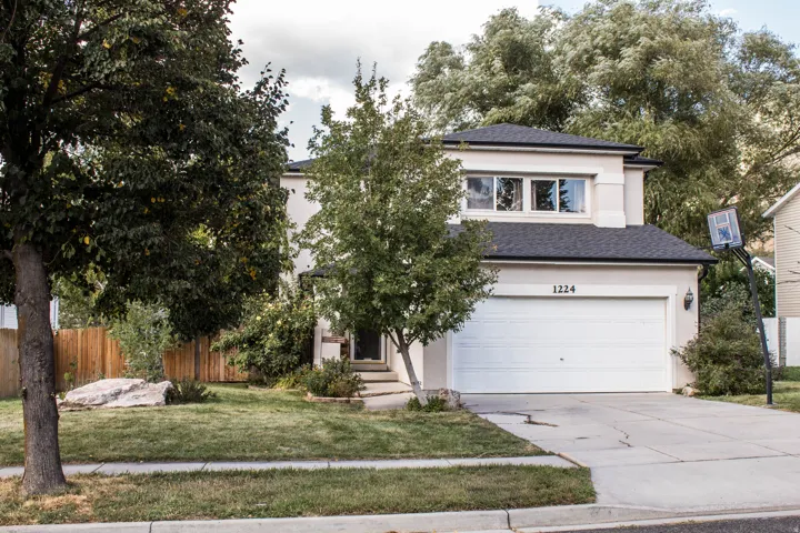 Stucco exterior with a dark shingle roof, integrated two-car garage, and a concrete driveway