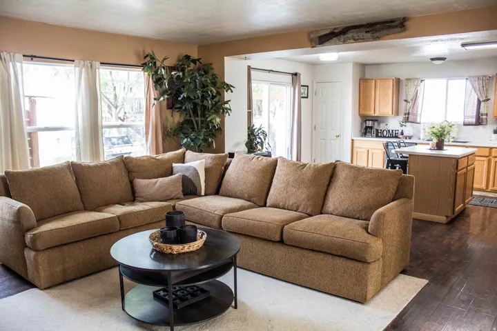 Open-concept living area featuring dark wood-finish flooring, multiple windows, and a kitchen with light wood cabinetry and a central island