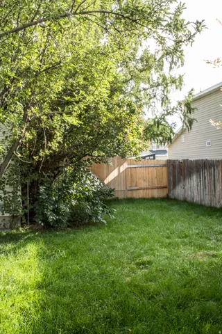 Expansive grassy yard with mature trees and wood fencing