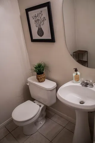 Pedestal sink with chrome-finish faucet, elongated toilet, and tile flooring