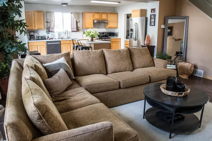 Open-concept living space featuring wood-finish flooring, a kitchen with light wood cabinetry, white countertops, and a stainless steel refrigerator