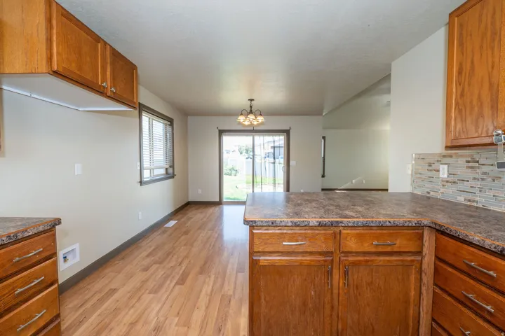 Kitchen featuring wood-finish cabinetry, patterned countertops, and a tiled backsplash