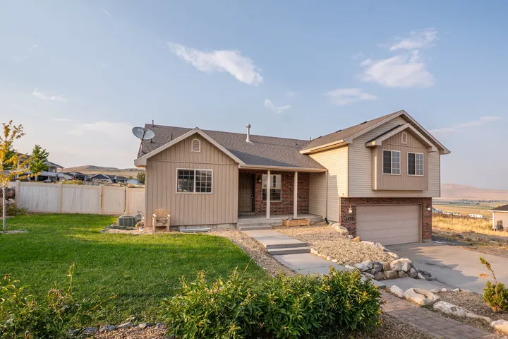Exterior featuring brick and siding finishes, an attached two-car garage, a covered front porch, and a fenced backyard