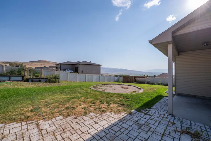 Expansive backyard featuring a concrete paver patio, a covered patio area, and a large lawn space