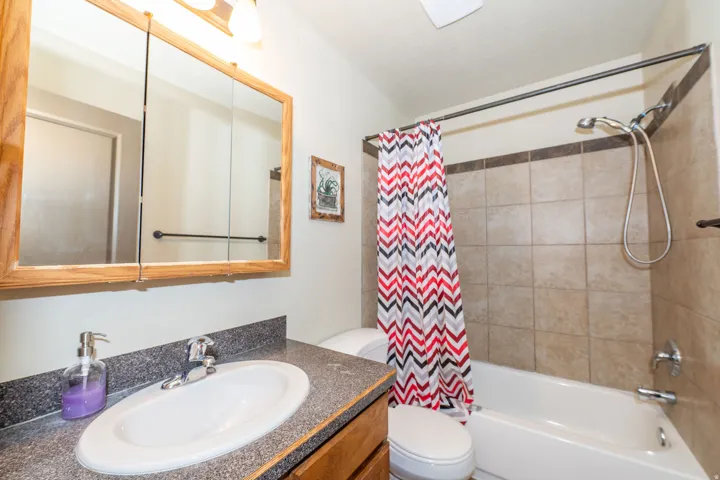 Vanity with an integrated sink, wood-finish cabinetry, and a framed medicine cabinet with overhead lighting