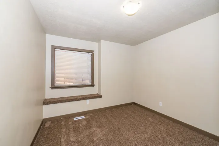 Carpeted room featuring a window with blinds, a window seat, and a flush mount ceiling light