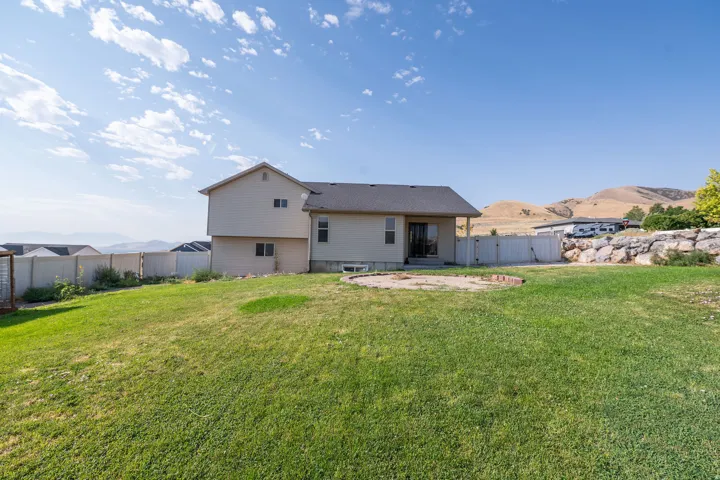 Expansive lawn with a partial privacy fence, rock retaining wall, and mountain scenery
