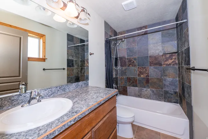 Bathroom vanity with a wood-finish cabinet, a single basin sink, and a granite-style countertop