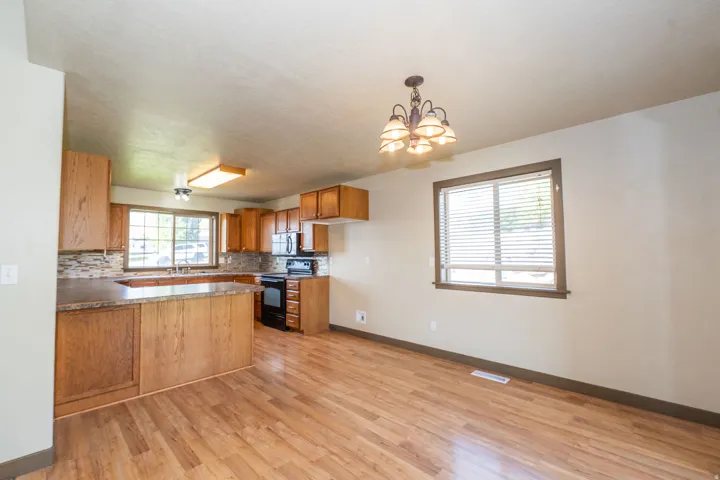 Kitchen featuring wood-finish flooring, wood cabinetry, built-in appliances, and a tile backsplash