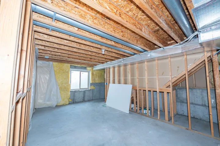Unfinished lower level with wood framing, concrete flooring, and exposed ceiling joists