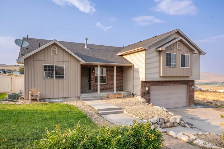 Multi-level residence featuring a two-car garage, brick and siding exterior, and a gabled roof