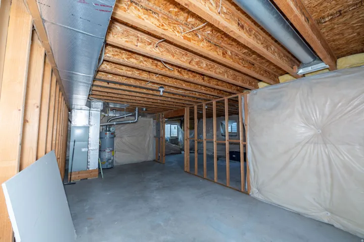 Unfinished basement with exposed wood framing, concrete flooring, and visible ductwork