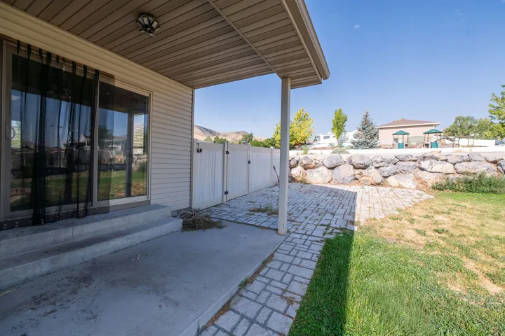 Covered patio with concrete flooring, sliding glass door entry, and an adjacent paver stone patio