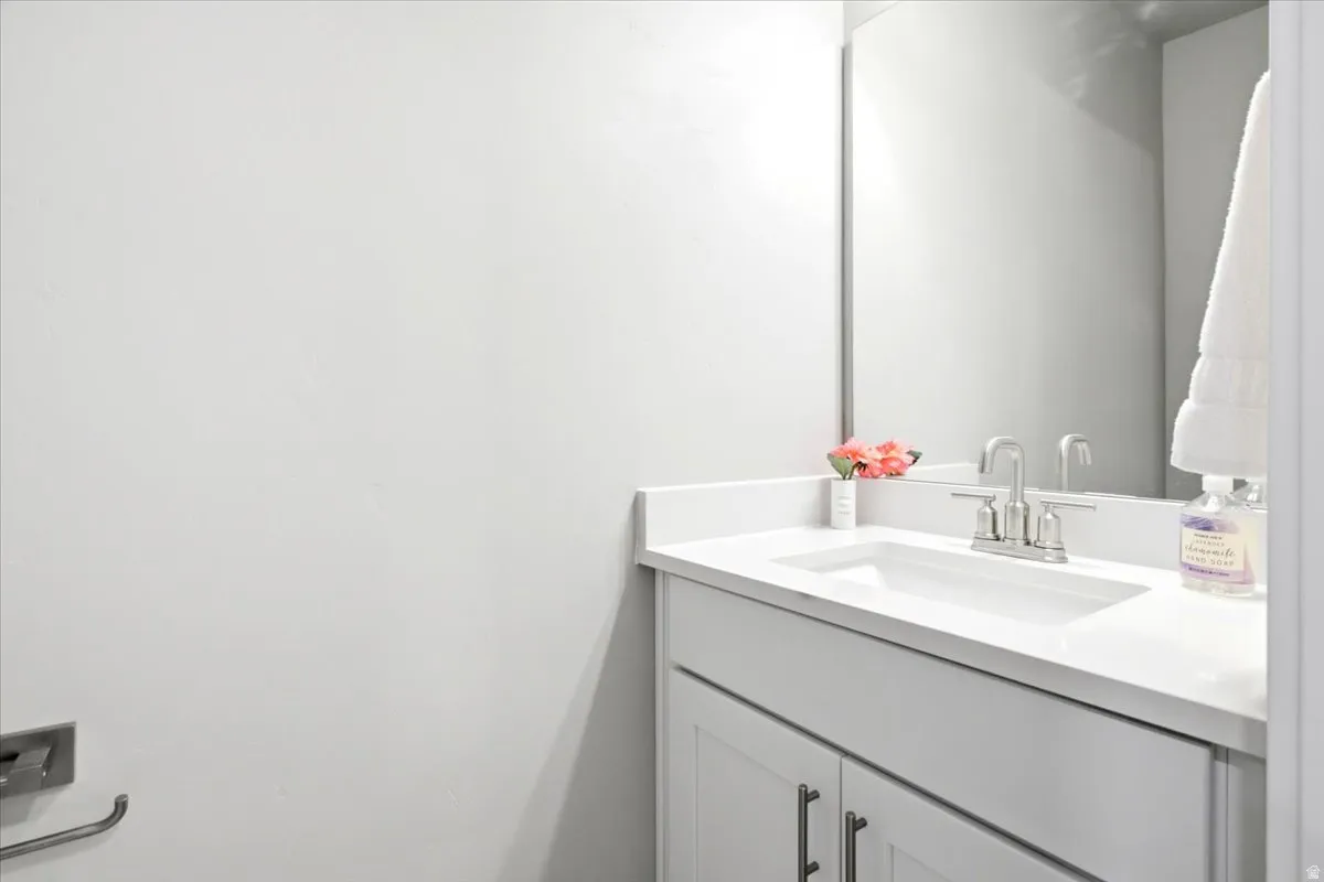 Modern bathroom vanity featuring a clean-lined white cabinetry base, white quartz countertop with an integrated sink, and chrome faucet fixtures