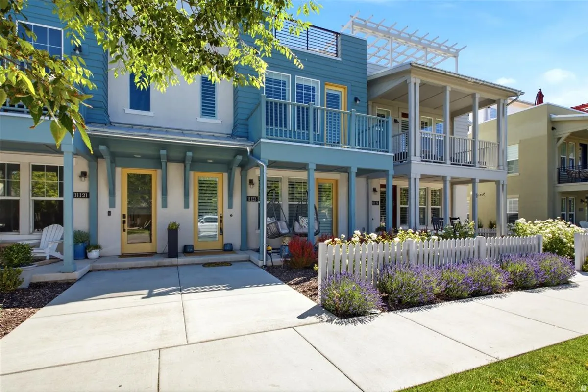 Two-story facade with blue siding and white stucco, featuring yellow-painted entry doors
