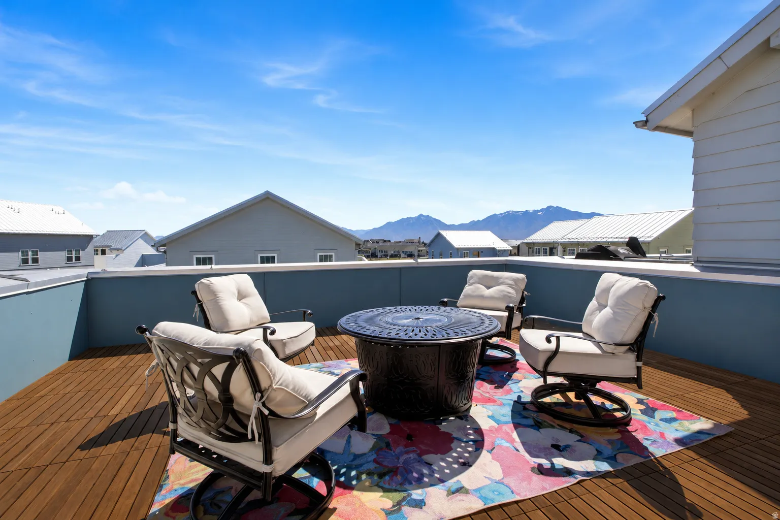 Rooftop deck featuring wood-finish flooring, a low perimeter wall, and distant mountain scenery. (Wood stain has been enhanced)