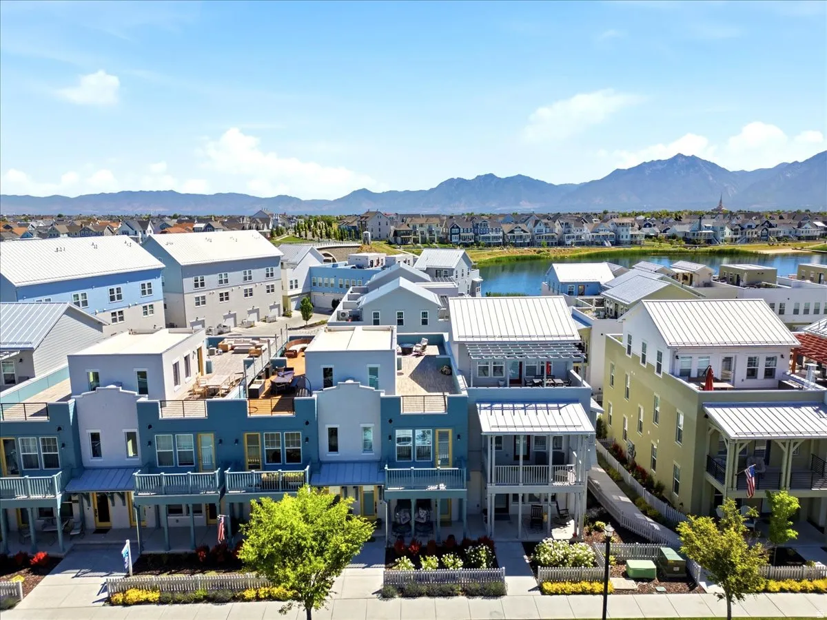 Mixed-use development with multi-story buildings, mountain backdrop, and a lake
