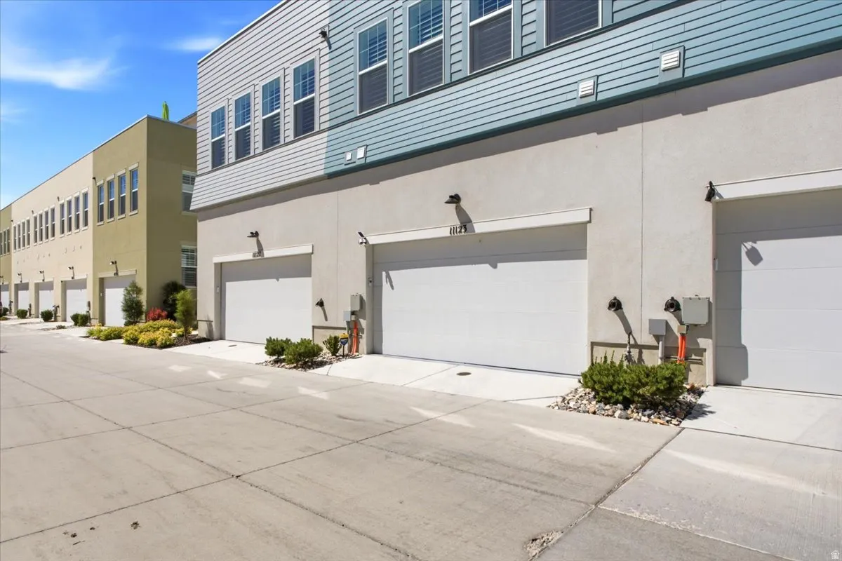 Multi-story building featuring horizontal siding, multiple windows with shutters, and a ground-level garage door