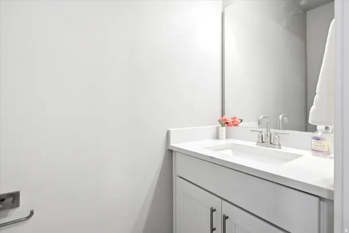Modern bathroom vanity featuring a clean-lined white cabinetry base, white quartz countertop with an integrated sink, and chrome faucet fixtures