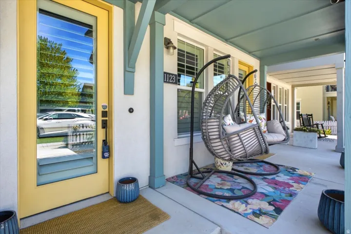 Covered porch with bright yellow entry door, natural light, and ceiling fans