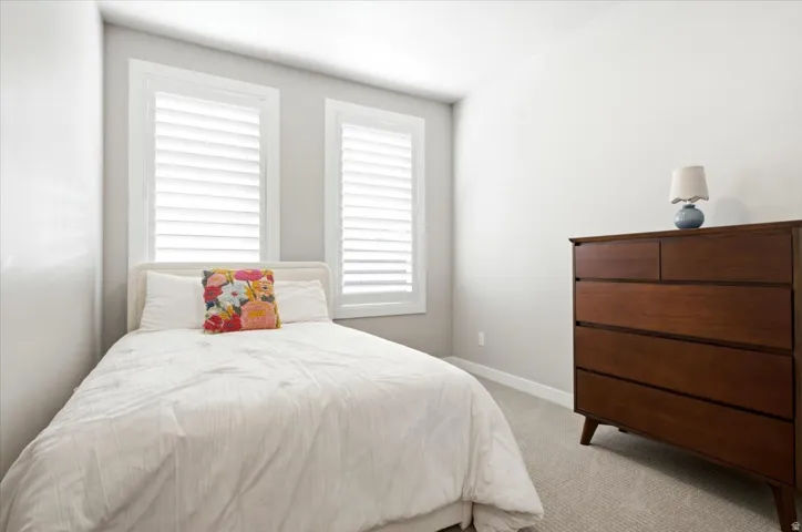 Dual windows with white plantation shutters, light-toned carpeting, and a neutral wall color
