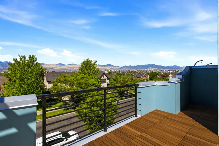 Rooftop deck featuring wood-finish tile flooring, metal railings, and blue exterior panels. (Wood stain has been enhanced)