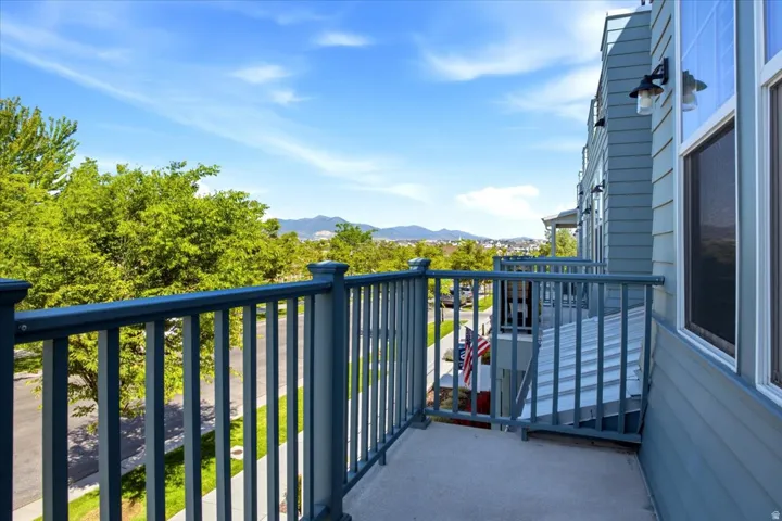 Balcony featuring metal railings, concrete flooring, exterior wall sconces, and siding exterior