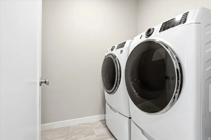Laundry area with light-colored walls and tile flooring