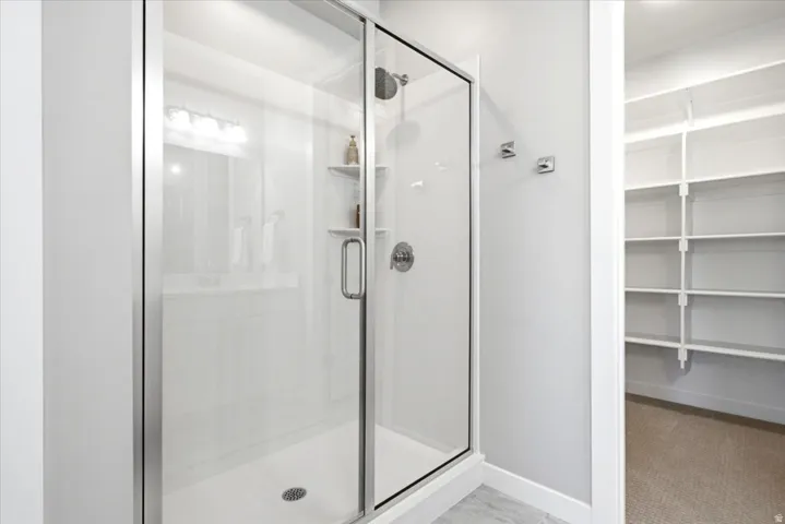 Enclosed shower with glass sliding door, integrated shelving, and stainless steel fixtures