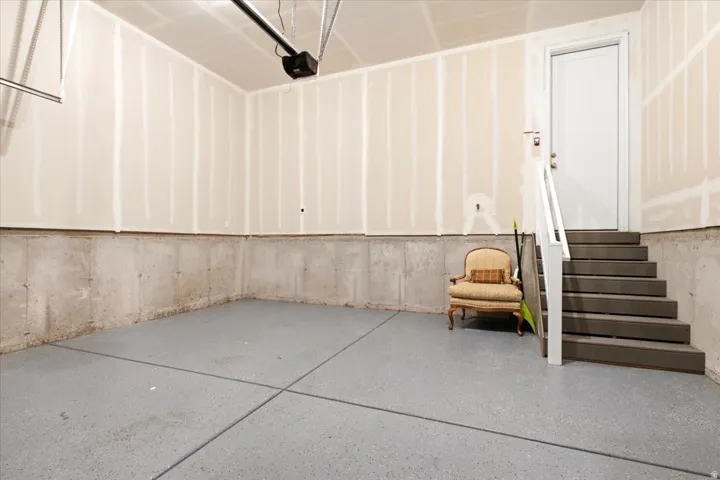 Garage space featuring a light gray speckled floor, concrete perimeter, and unfinished walls