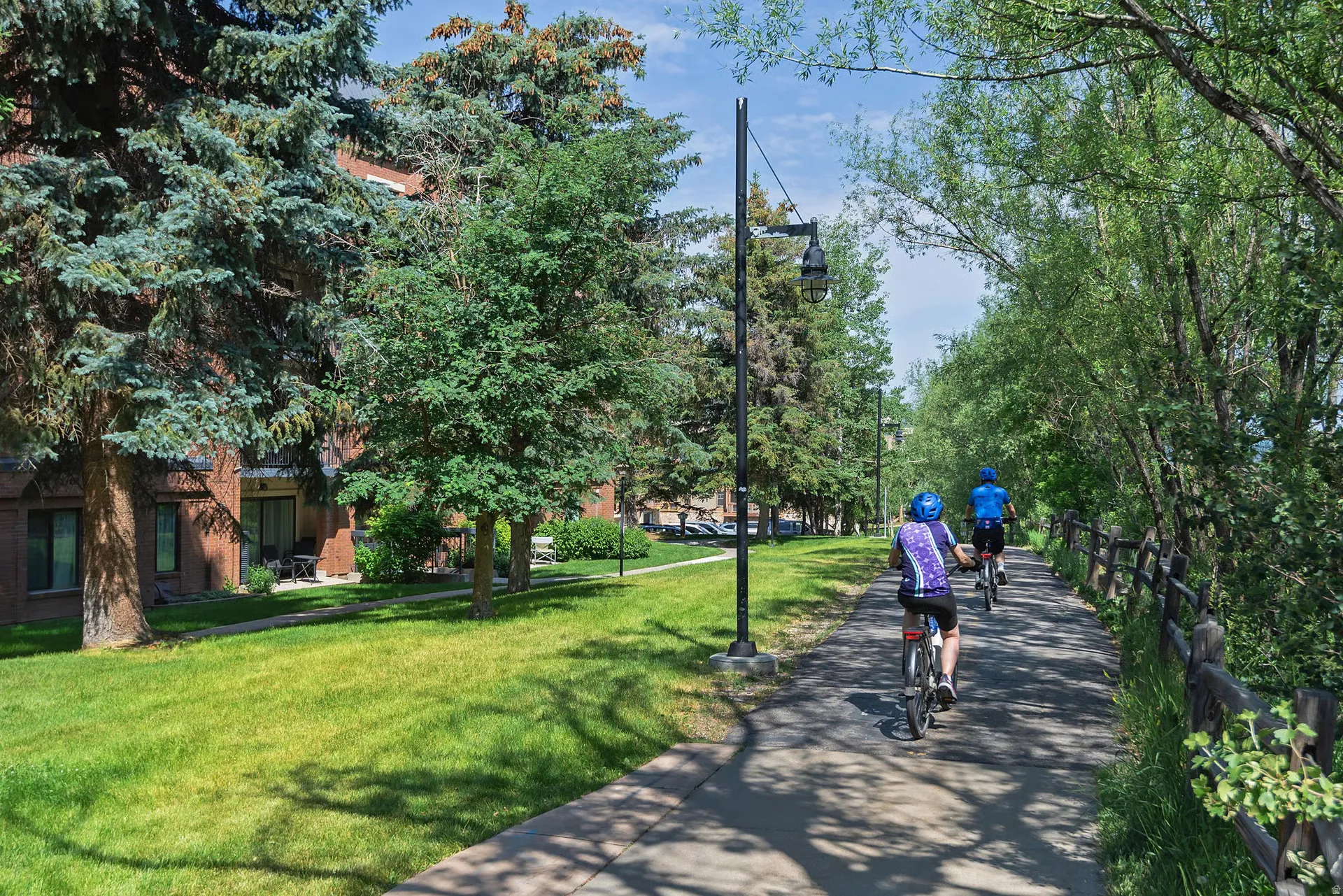 Paved pathway bordered by a rustic wooden fence and mature trees