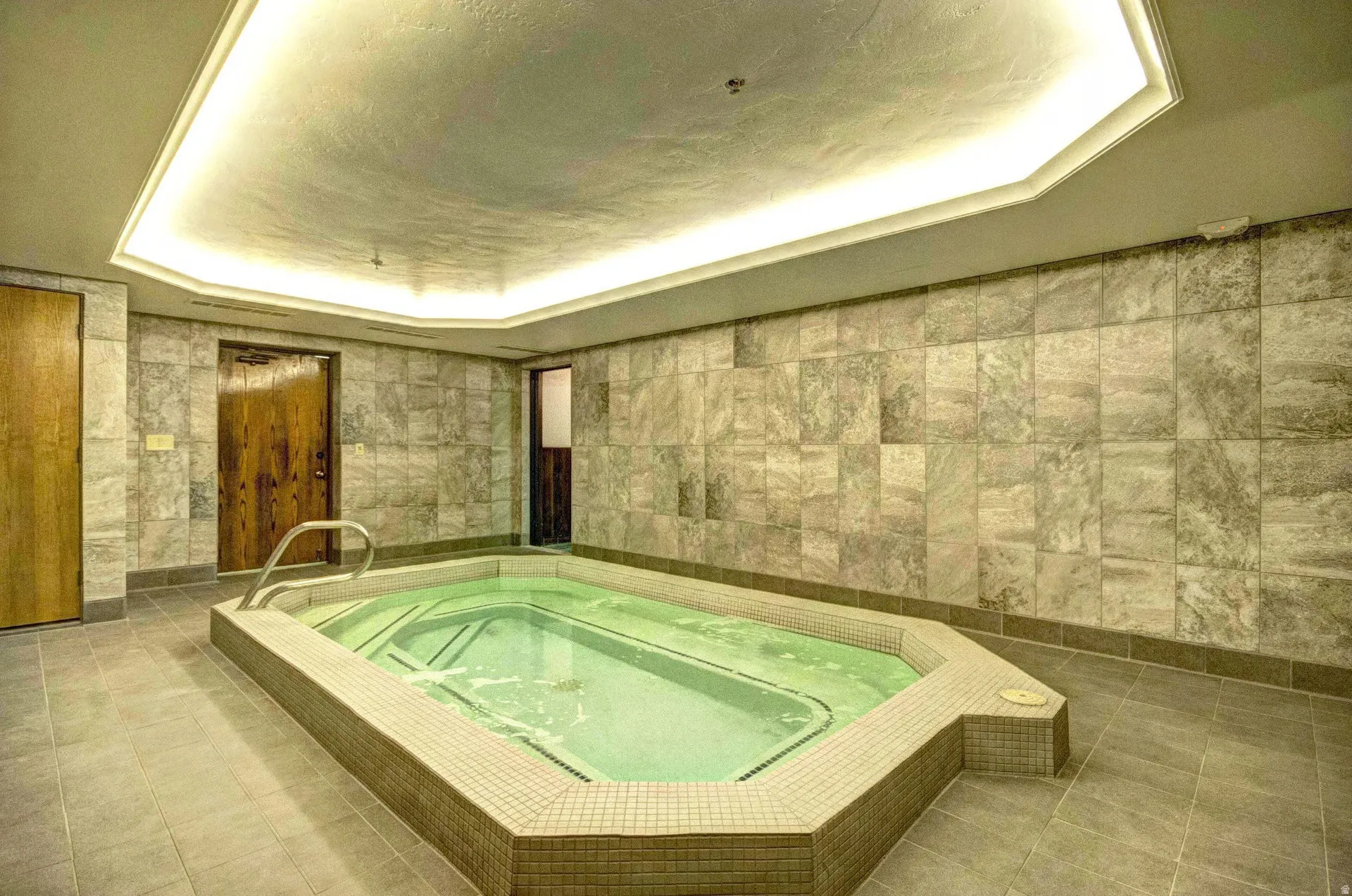 Indoor spa with an octagonal perimeter, surrounded by large format wall tile and coordinating floor tile