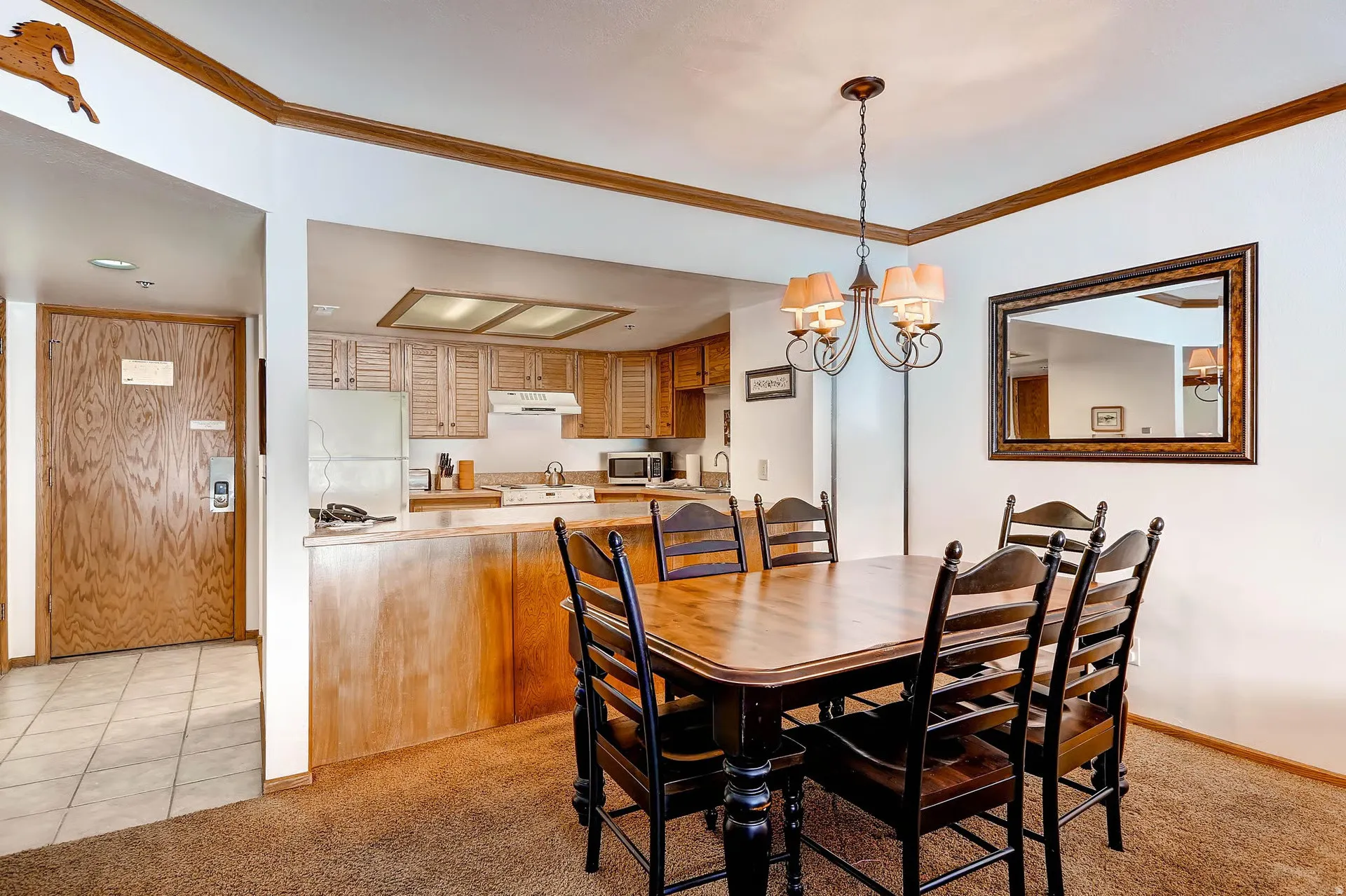 Dining area featuring a bronze chandelier, wood-finish flooring, and a framed wall mirror