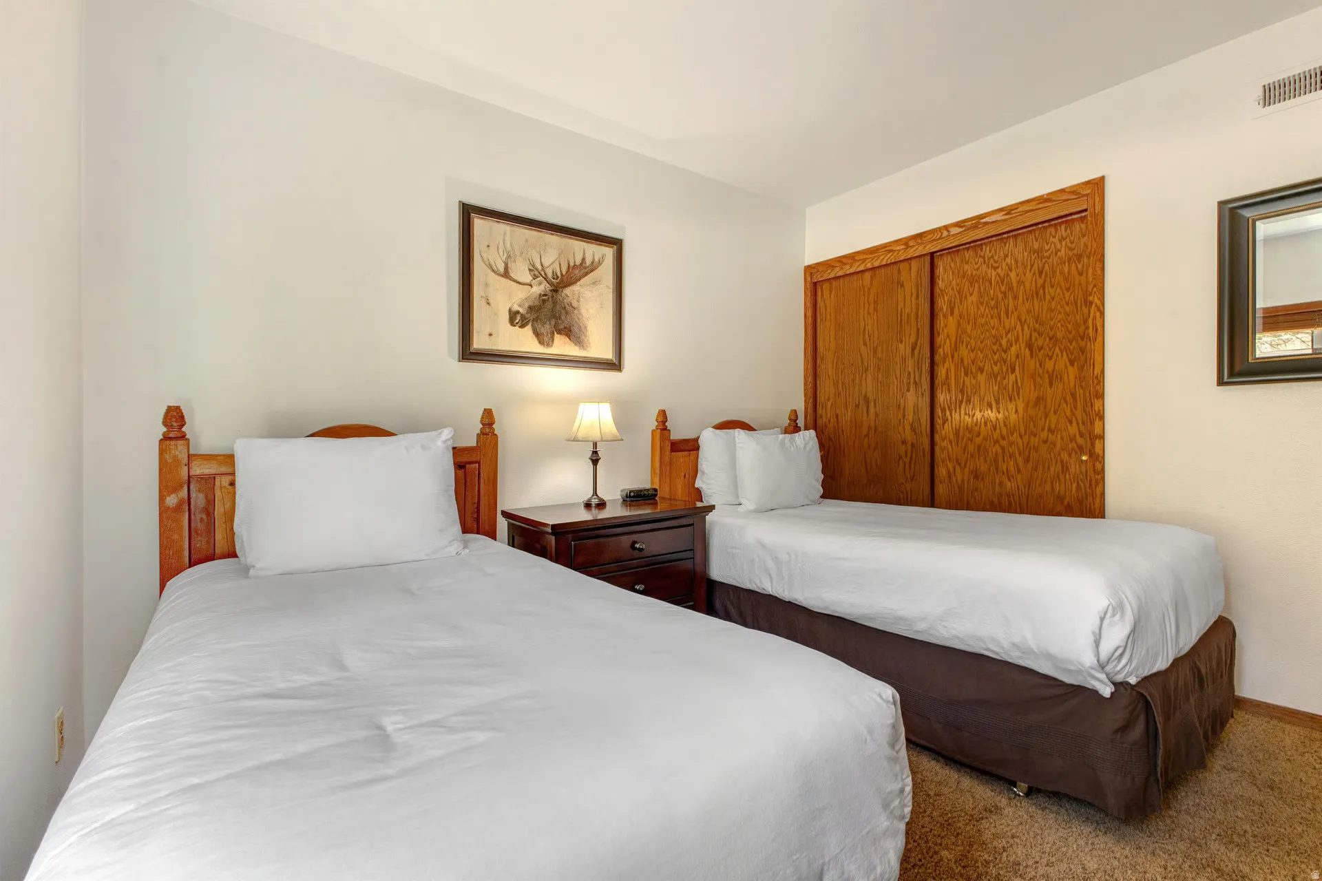 Bedroom featuring two twin beds with wood-finish headboards, a dark wood-finish nightstand, and a matching dark wood-finish closet with sliding doors