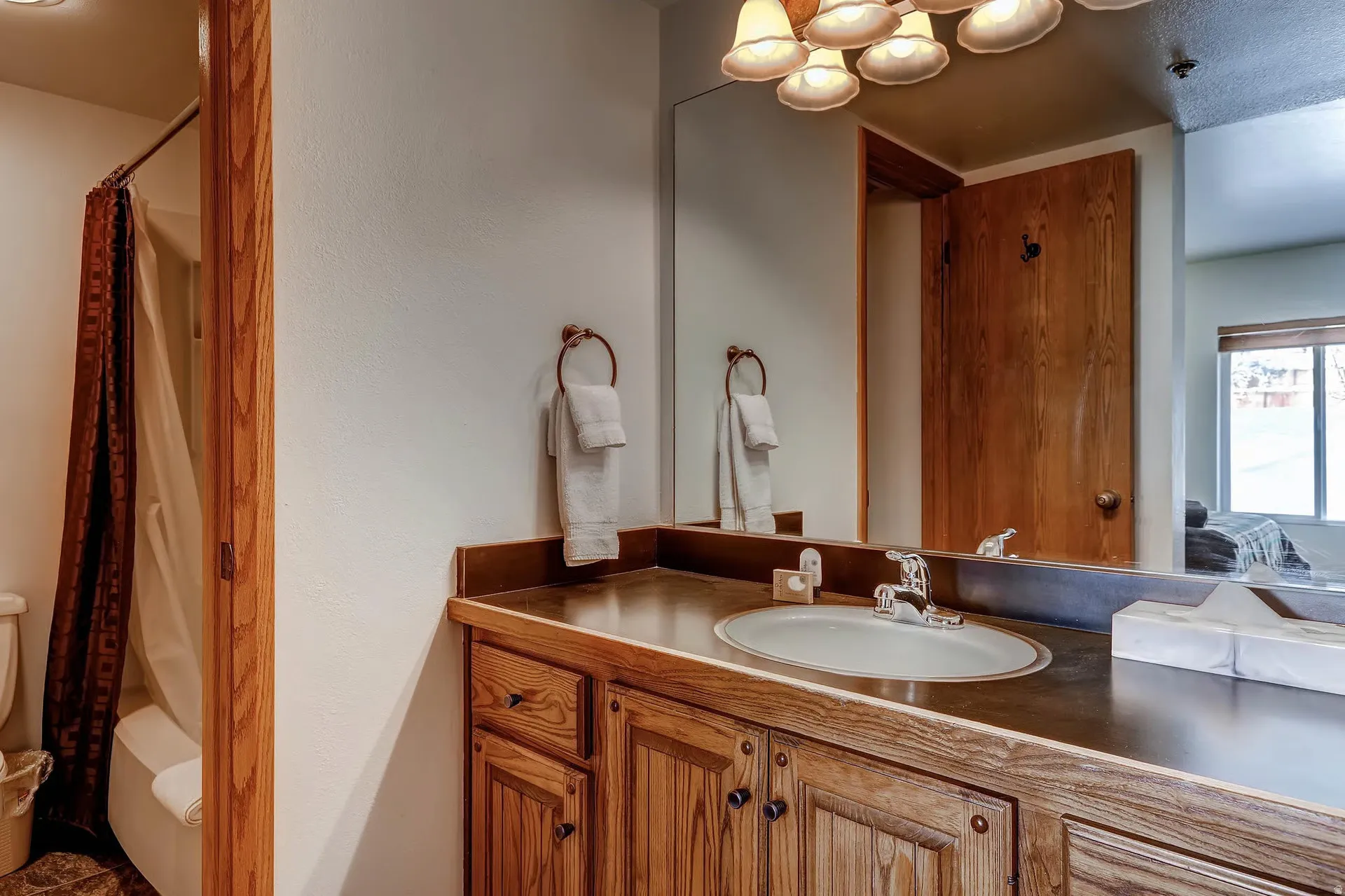 Bathroom vanity featuring wood-finish cabinetry, integrated sink, and bronze hardware
