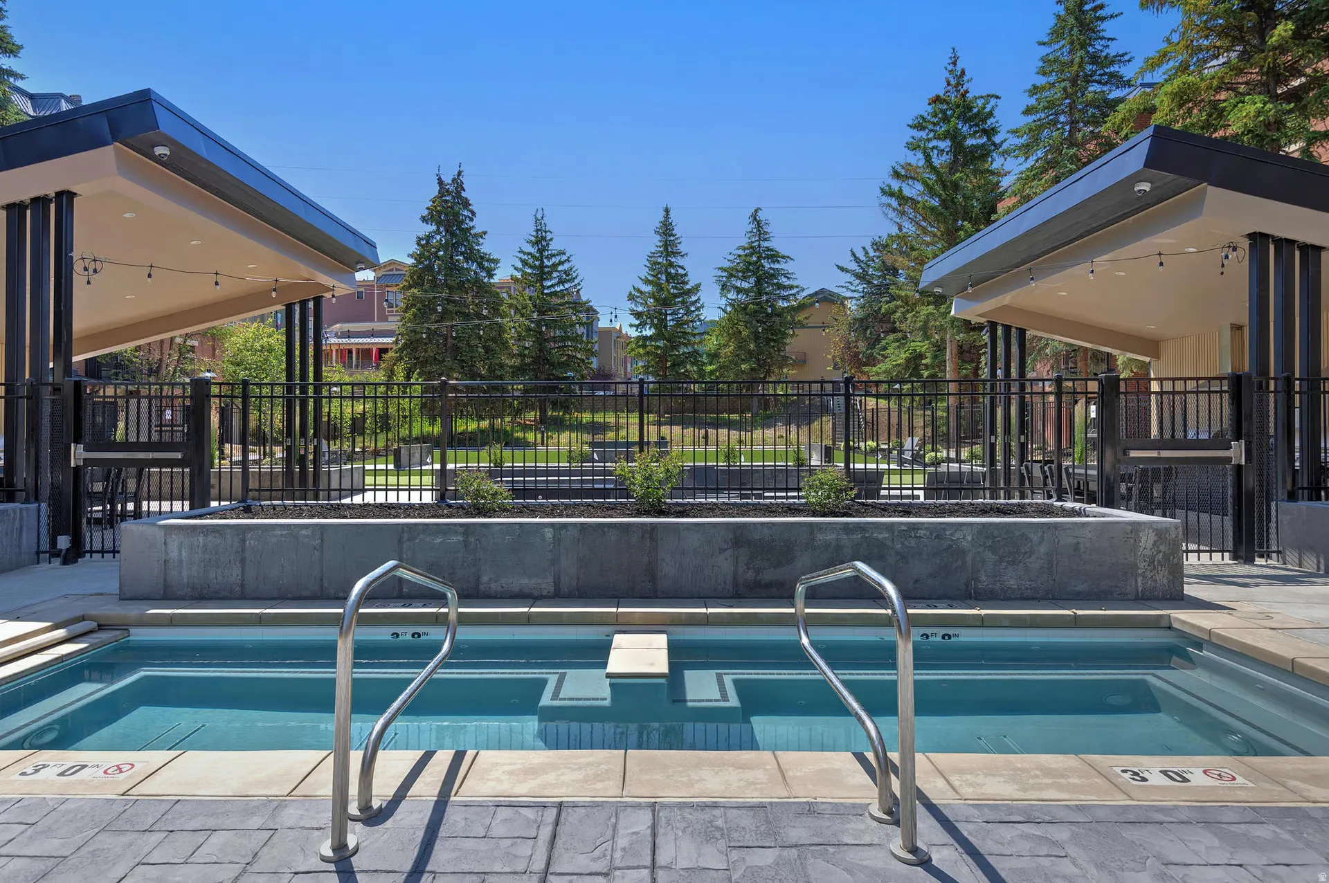 Dual hot tubs featuring integrated steps and stainless steel handrails, surrounded by patterned concrete pavers