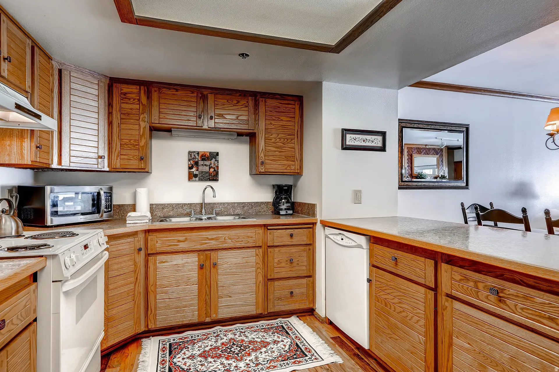 Kitchen featuring wood cabinetry, white appliances, and light-toned countertops