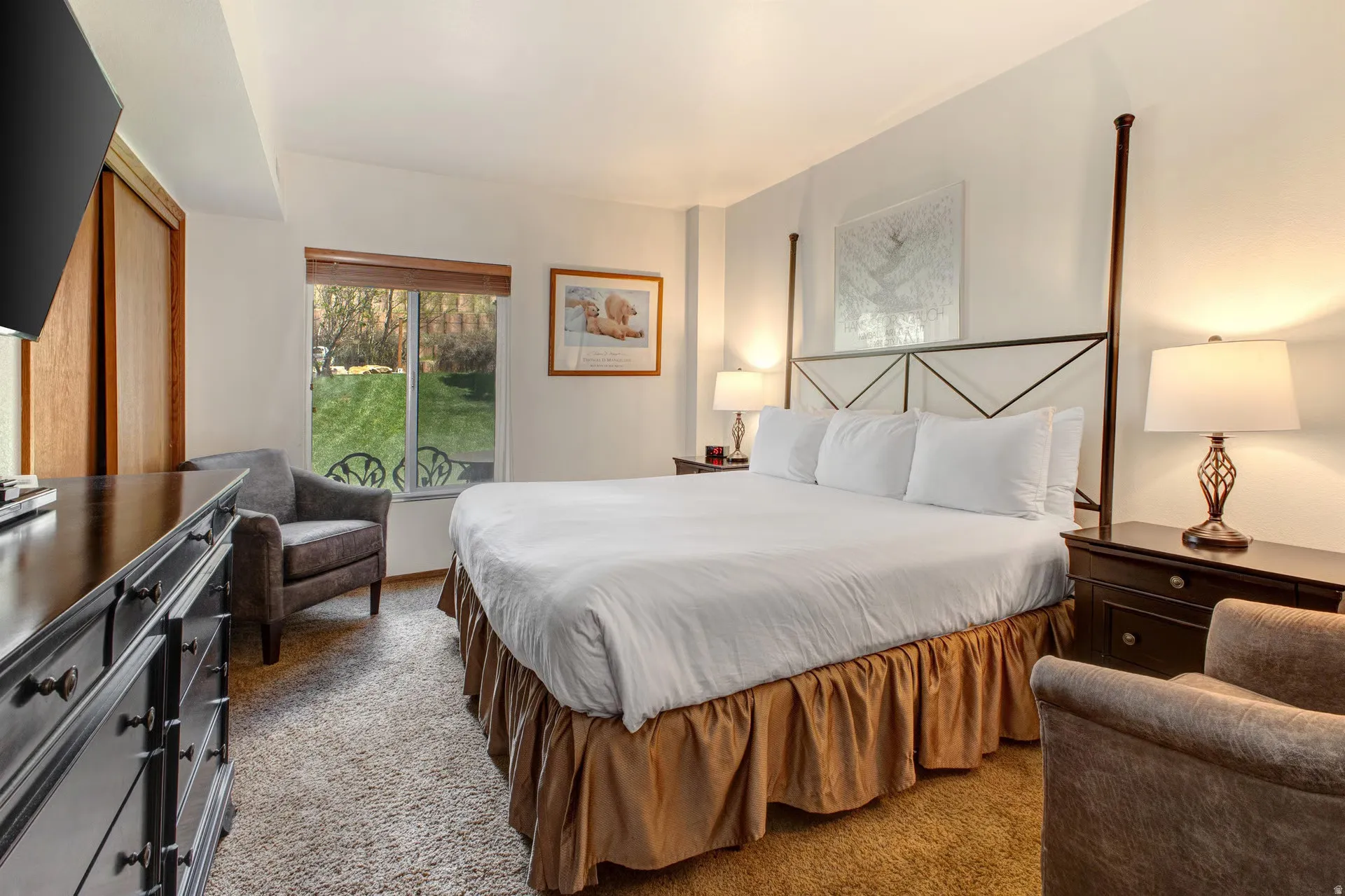 Carpeted interior space featuring a large window with outdoor landscape, a dark wood-finish dresser, and built-in wood closet doors