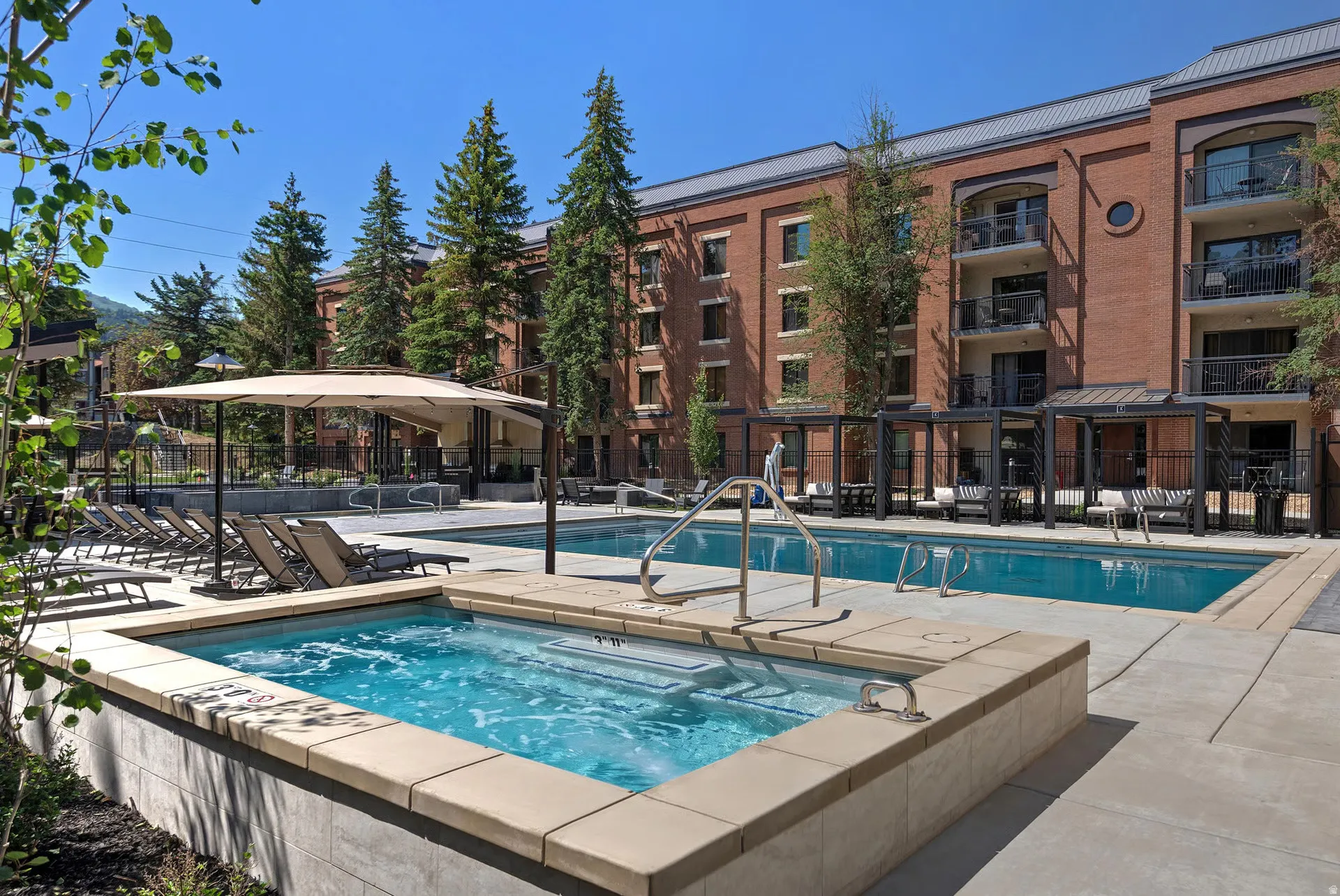 Outdoor amenity area featuring a spa, swimming pool, and concrete decking
