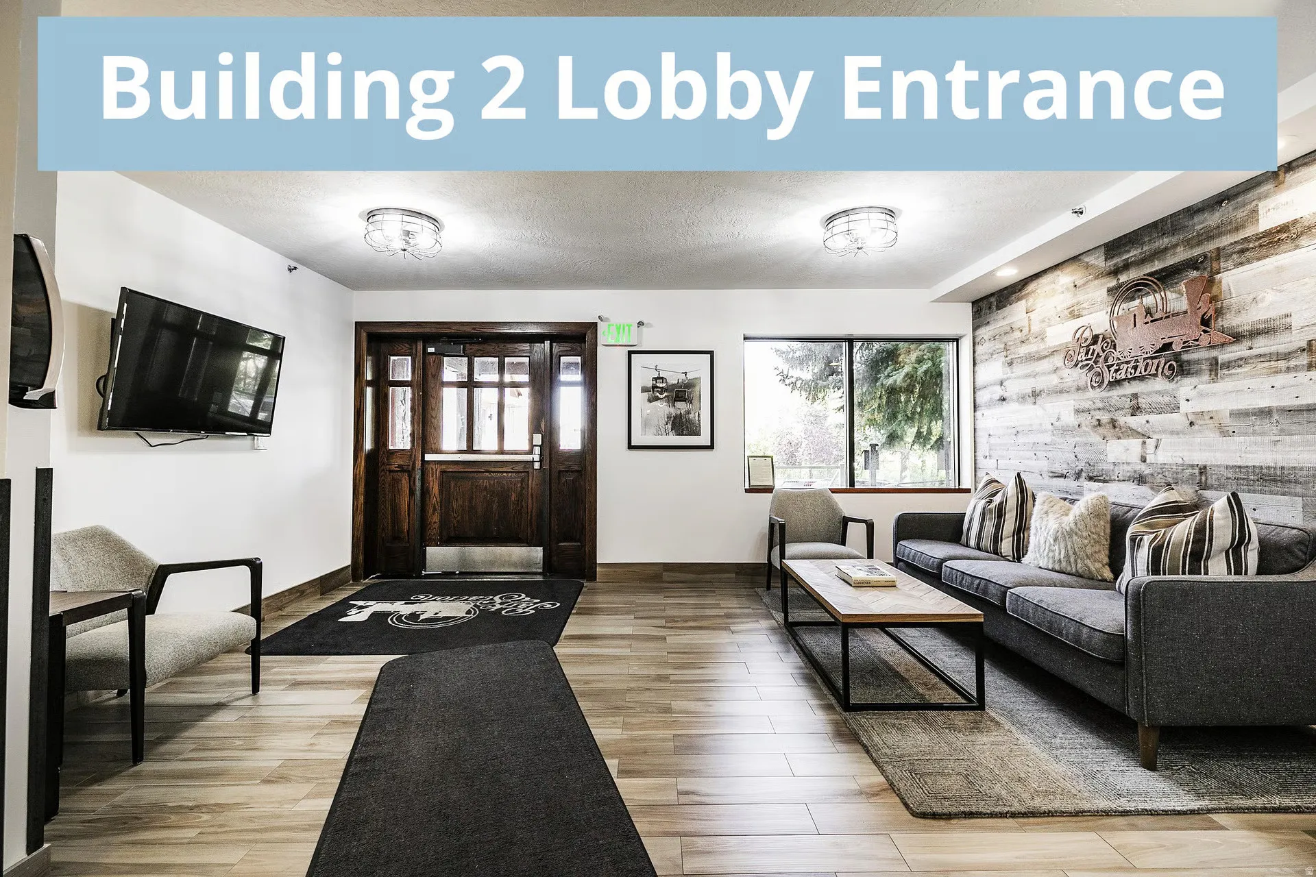 Lobby entrance featuring wood-finish flooring, a decorative shiplap accent wall, built-in wall-mounted television, large window, and recessed lighting fixtures
