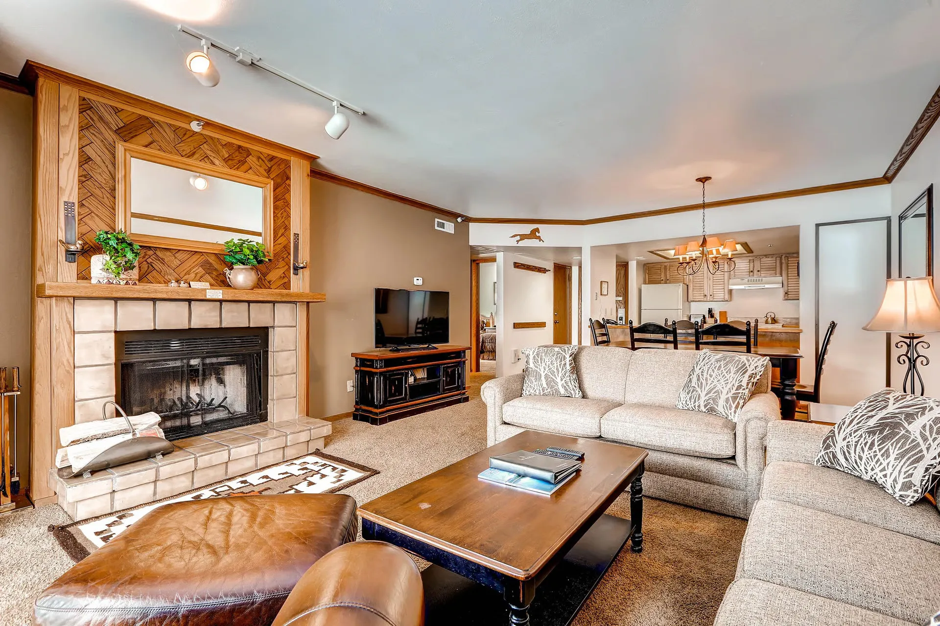 Living area featuring a stone surround fireplace with a wood mantle, wood-paneled accent wall, and track lighting