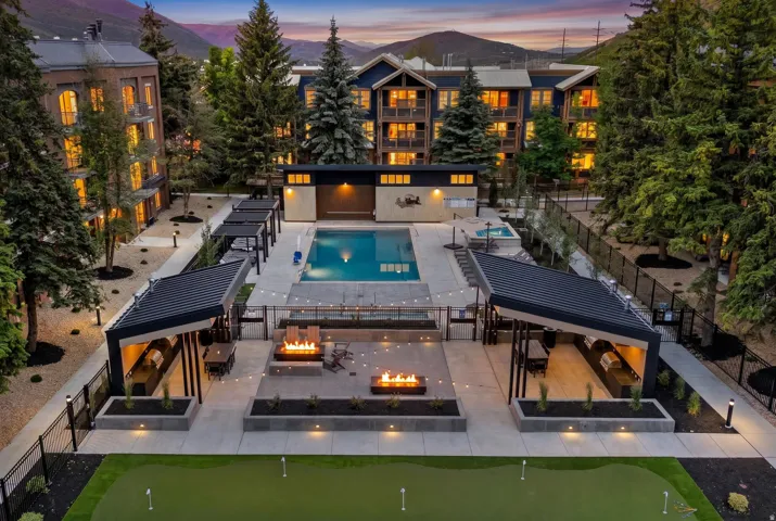 Outdoor amenity area featuring a swimming pool, spa, and two covered grilling stations with built-in barbecue units