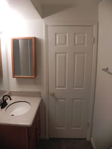 Wood-finish vanity with a drop-in sink, speckled countertop, and black-finish faucet