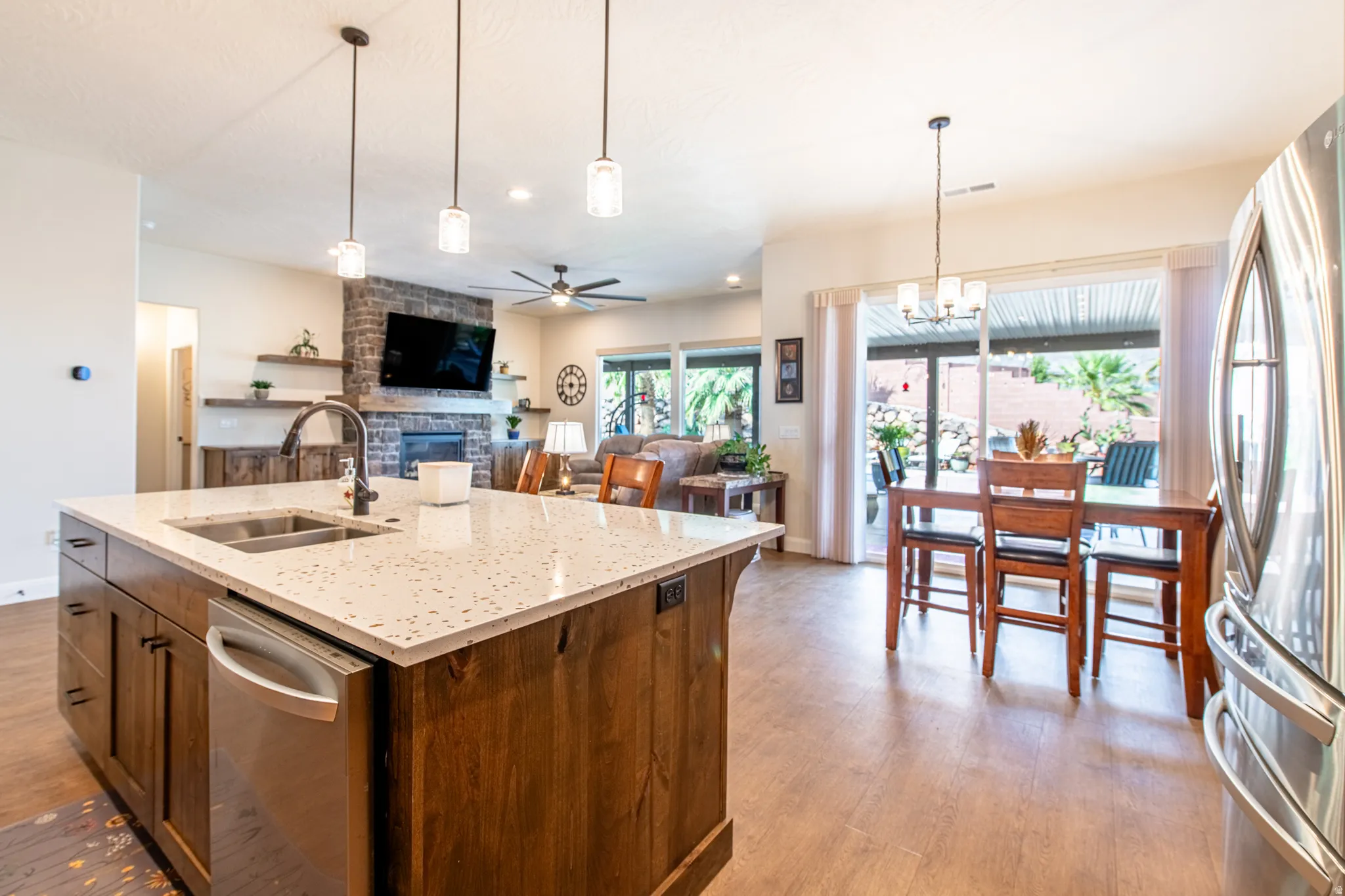 Kitchen island with integrated sink, stainless steel dishwasher, and pendant lighting