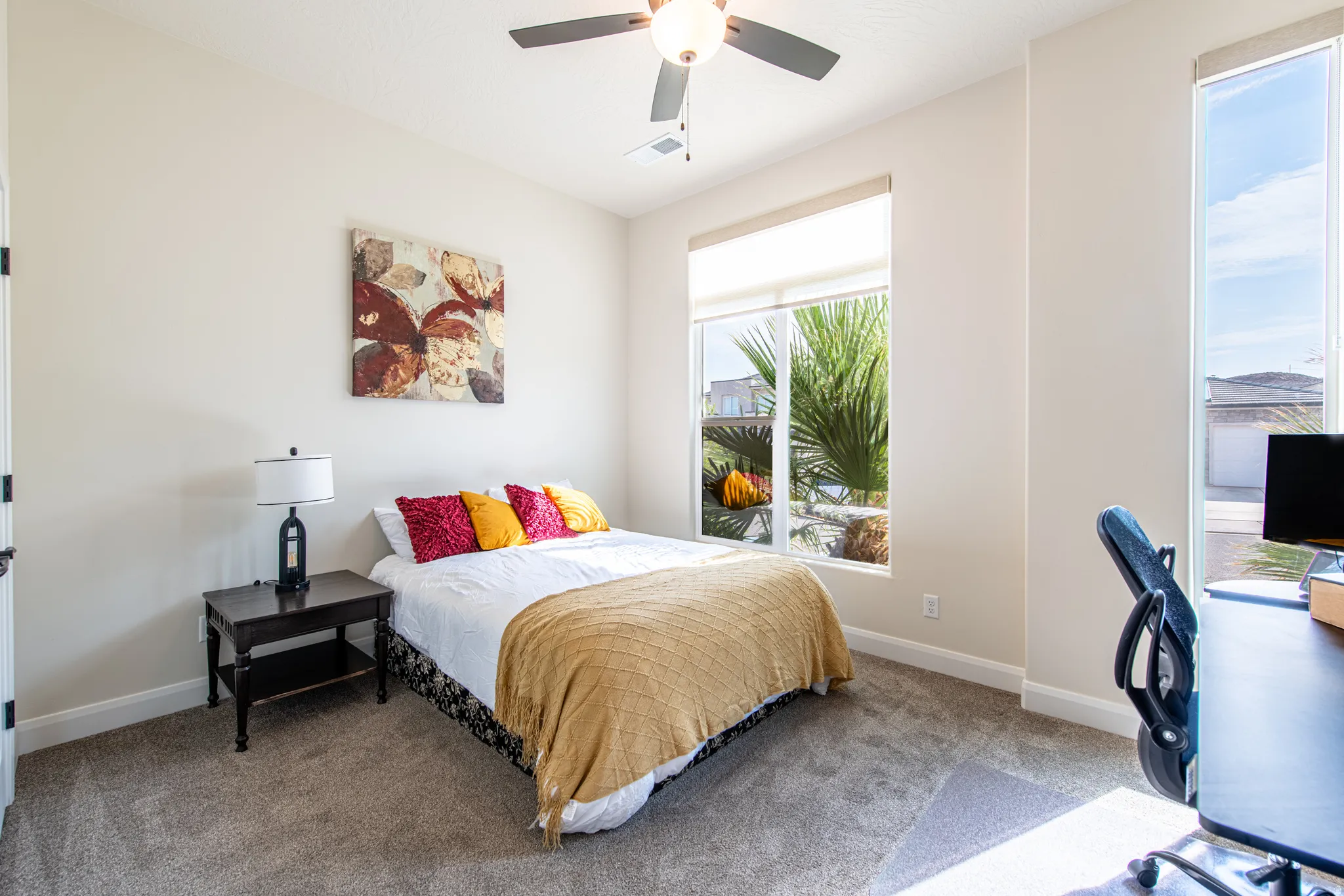 Neutral tone walls, ceiling fan, carpet flooring, and multiple windows